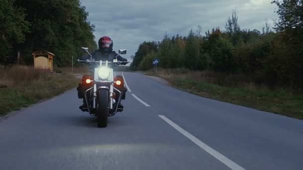 A man rides a motorcycle down a road in forest — Stock Video