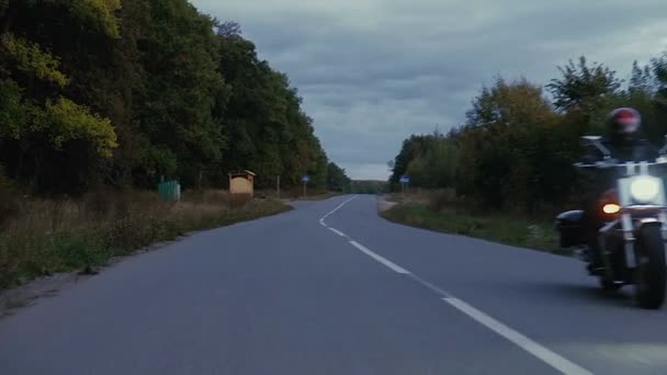 Mann fährt mit Motorrad eine Straße im Wald hinunter — Stockvideo