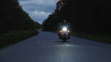 Bir adam bir motosiklet orman içinde bir yola rides
