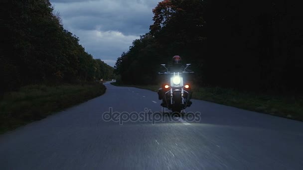Mann fährt mit Motorrad eine Straße im Wald hinunter — Stockvideo