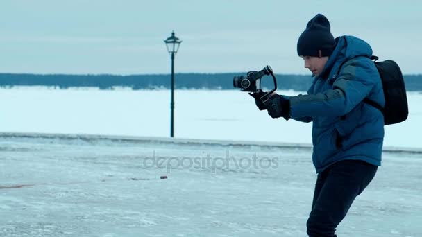 Χειριστής κάμερας με τα πόδια με ηλεκτρονικό σταθεροποιητή το χειμώνα — Αρχείο Βίντεο