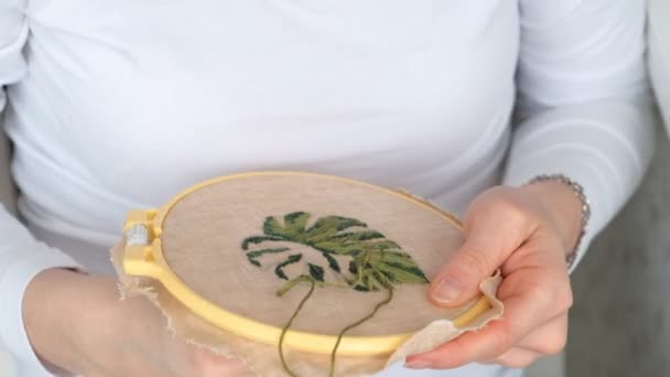 A menina está bordando uma imagem de uma folha de flor no tecido. Artesanato doméstico — Vídeo de Stock