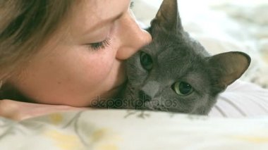 El yatakta uyuyan bir yaşlı kadın gri okşayarak kedi