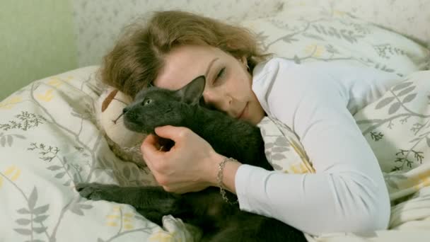 Χέρι του μια ηλικιωμένη γυναίκα χαϊδεύοντας γκρίζα γάτα κοιμάται στο κρεβάτι — Αρχείο Βίντεο