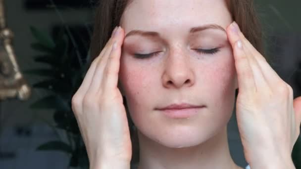 El retrato de una mujer joven con la piel perfecta aplicando una crema de noche de día en su rostro previamente limpiado. Concepto de cuidado de la piel, cosméticos, belleza, centro de bienestar, tratamiento facial, masaje facial — Vídeos de Stock