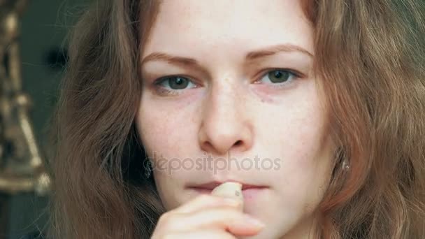 Schöne Blondine, die ihre Lippen mit Lippenstift schminkt, während der Wind ihre Haare weht — Stockvideo