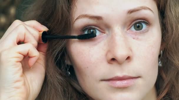 Eye in macro footage of young woman applying mascara on eyelashes — Stock Video