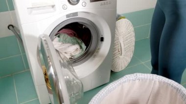 Ev hanımı çamaşır makinesi çamaşır sepeti üzerinden doldurur ve kapı kilitleri makine