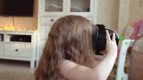 Niña con camisa blanca viendo 360 videos en casa, con auriculares VR . — Vídeo de stock