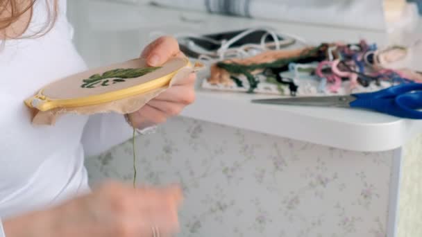 Kvinnan brodera en bild av en blomma blad på tyget. Hem hantverk — Stockvideo