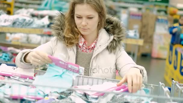 Una giovane donna in un supermercato compra vestiti — Video Stock