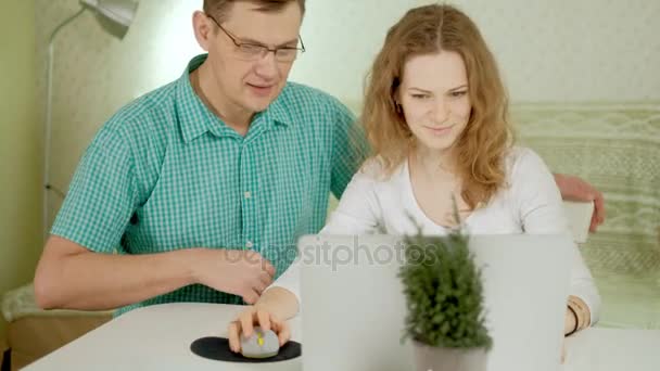 Smiling young couple using laptop at home emotionally discuss — Stock Video