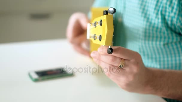 Ένας άνδρας προσαρμόζει το γιουκαλίλι χρησιμοποιώντας την εφαρμογή στο τηλέφωνο — Αρχείο Βίντεο