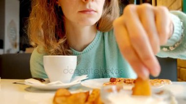 Bir kadın bir kafede soslu kızarmış patates yiyor