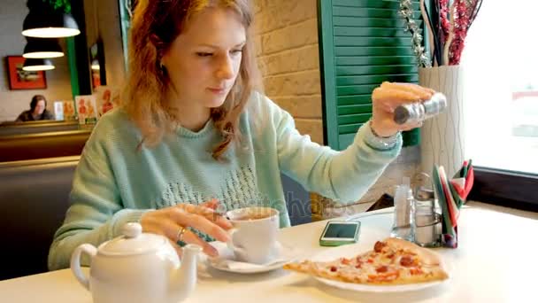 Молода красива жінка в ресторані їсть піцу і п'є чай — стокове відео