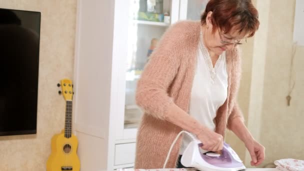 Alte Frau bügelt Kleidung zu Hause — Stockvideo