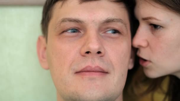 Женщина шепчет мужчинам на ухо, эмоции на лице — стоковое видео