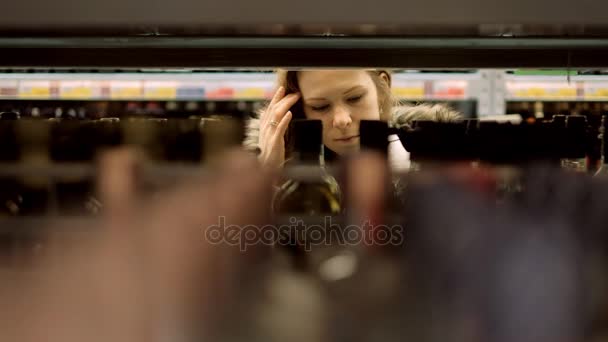 Uma jovem em um supermercado compra vinho — Vídeo de Stock