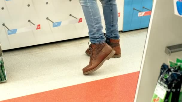 Γυναίκα σε ένα κατάστημα παπουτσιών επιλέγει μπότες προσπαθεί — Αρχείο Βίντεο
