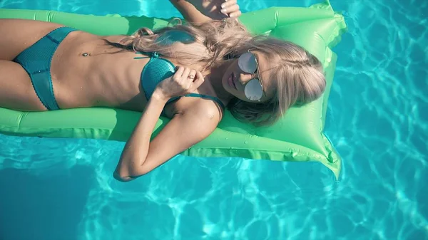 Ung vacker kvinna liggande på luftmadrass i poolen — Stockfoto