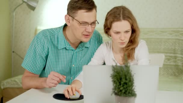 Smiling young couple using laptop at home emotionally discuss — Stock Video