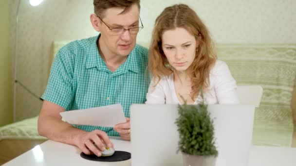 Sorridente giovane coppia utilizzando computer portatile a casa emotivamente discutere — Video Stock