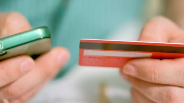 Мужчина покупает товар в интернет-магазине и платит кредитной картой через ее телефон — стоковое видео