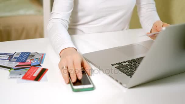 Une jeune femme achète des biens dans une boutique en ligne et paie une carte de crédit via son téléphone — Video