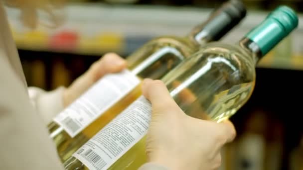 A young woman in a supermarket buys wine — Stock Video