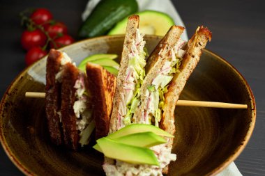 Tahta arka planda marul, jambon, peynir ve domatesli sağlıklı sandviç tostu.