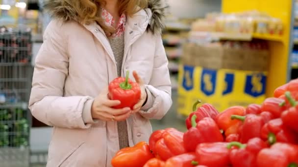 Una joven en un supermercado compra pimiento rojo — Vídeos de Stock