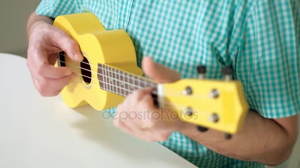 Мужчина играет на укулеле желтого цвета — стоковое видео