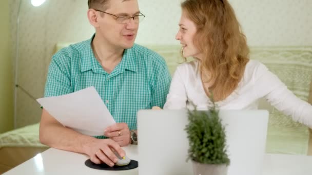 Sorridente giovane coppia utilizzando computer portatile a casa emotivamente discutere — Video Stock