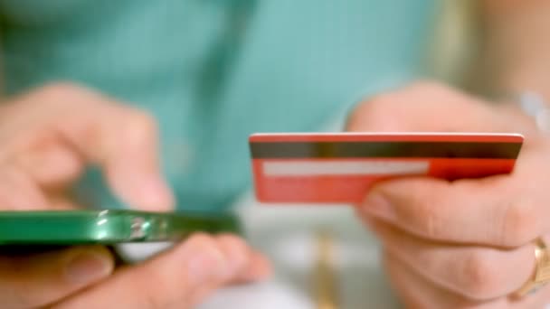 A man buys goods in an online store and pays a credit card through her phone — Stock Video