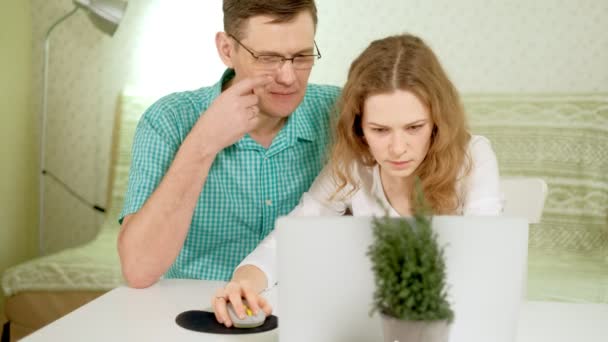 Smiling young couple using laptop at home emotionally discuss — Stock Video