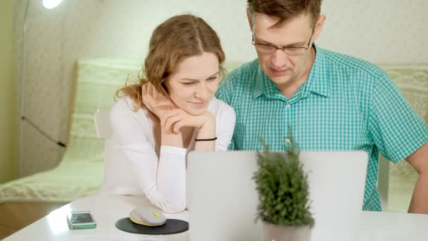 Συζητήστε χαμογελώντας νεαρό ζευγάρι που χρησιμοποιούν φορητό υπολογιστή στο σπίτι συναισθηματικά — Αρχείο Βίντεο