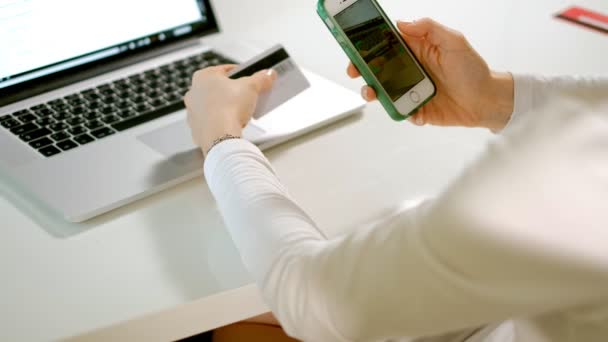 Een jonge vrouw koopt goederen in een online winkel en een credit card betaalt via haar telefoon — Stockvideo