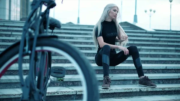 Güzel kadın uzun boylu buildin yakınındaki bir bisiklet ile gidiyor — Stok fotoğraf