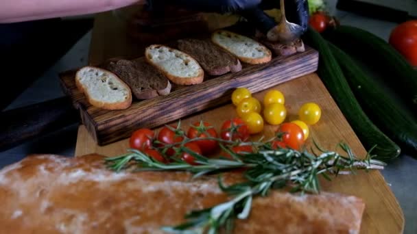 Hombre preparando bruschetta italiana con tomates al horno, albahaca y queso. Comida italiana cámara lenta — Vídeos de Stock