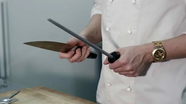Chef afila un cuchillo en la cocina del restaurante —  Fotos de Stock