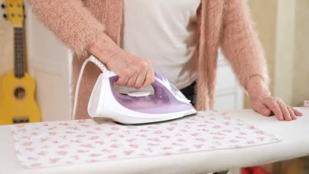 Стара жінка прасує одяг вдома — стокове відео