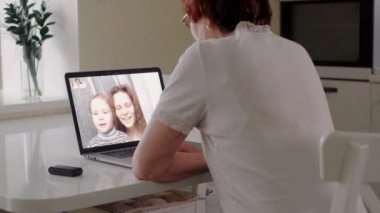 yaşlı kadın torunu ile bir dizüstü bilgisayar kullanarak skype üzerinden konuşmak