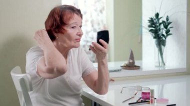 yaşlı kadın evde bir ayna önünde bir makyaj yapar