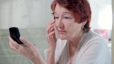 yaşlı kadın evde bir ayna önünde bir makyaj yapar