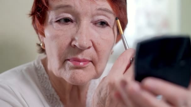 Vieille femme fait un maquillage devant un miroir à la maison — Video