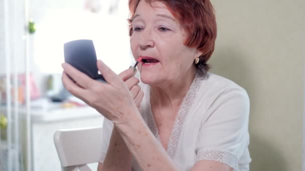 Oude vrouw maakt een make-up voor een spiegel thuis — Stockvideo