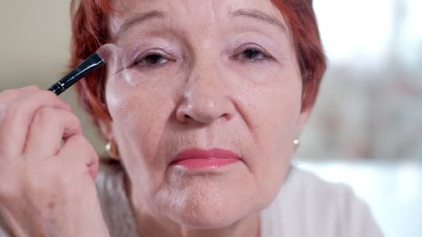 Старушка делает макияж перед зеркалом дома — стоковое видео