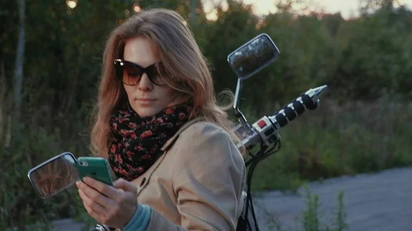 Kahverengi saçlı genç kız bir road yakınındaki bir motosiklet üzerinde oturur. — Stok fotoğraf