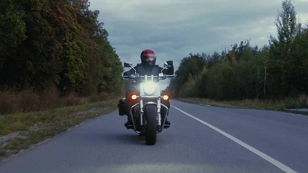 Un hombre conduce una motocicleta por un camino en el bosque — Foto de Stock