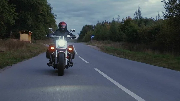 Mężczyzna jedzie na motocyklu w dół drogi w lesie — Zdjęcie stockowe